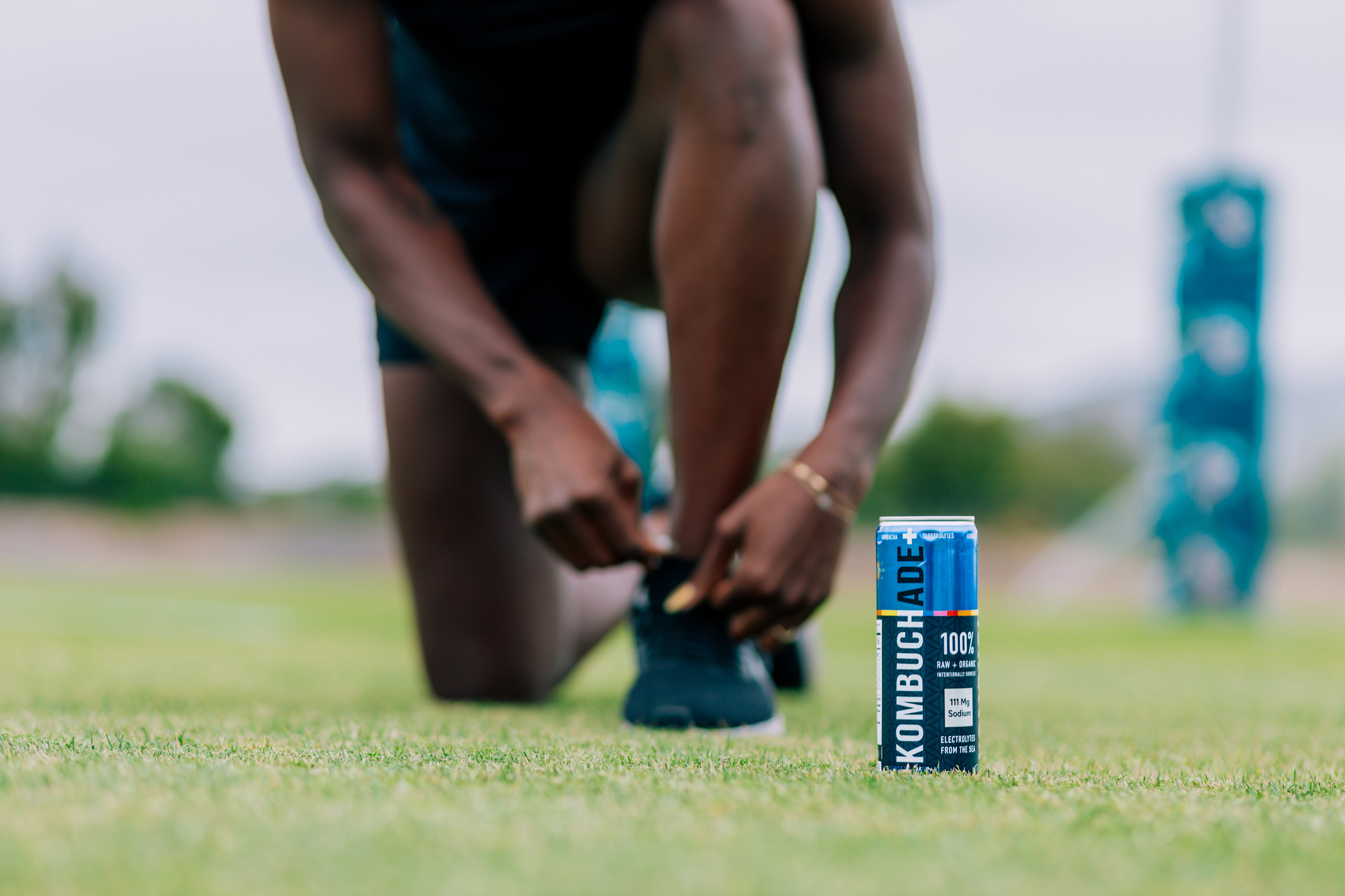 rugby athlete tying shoe on ruby field with a can of lavender lemonade Kombuchade