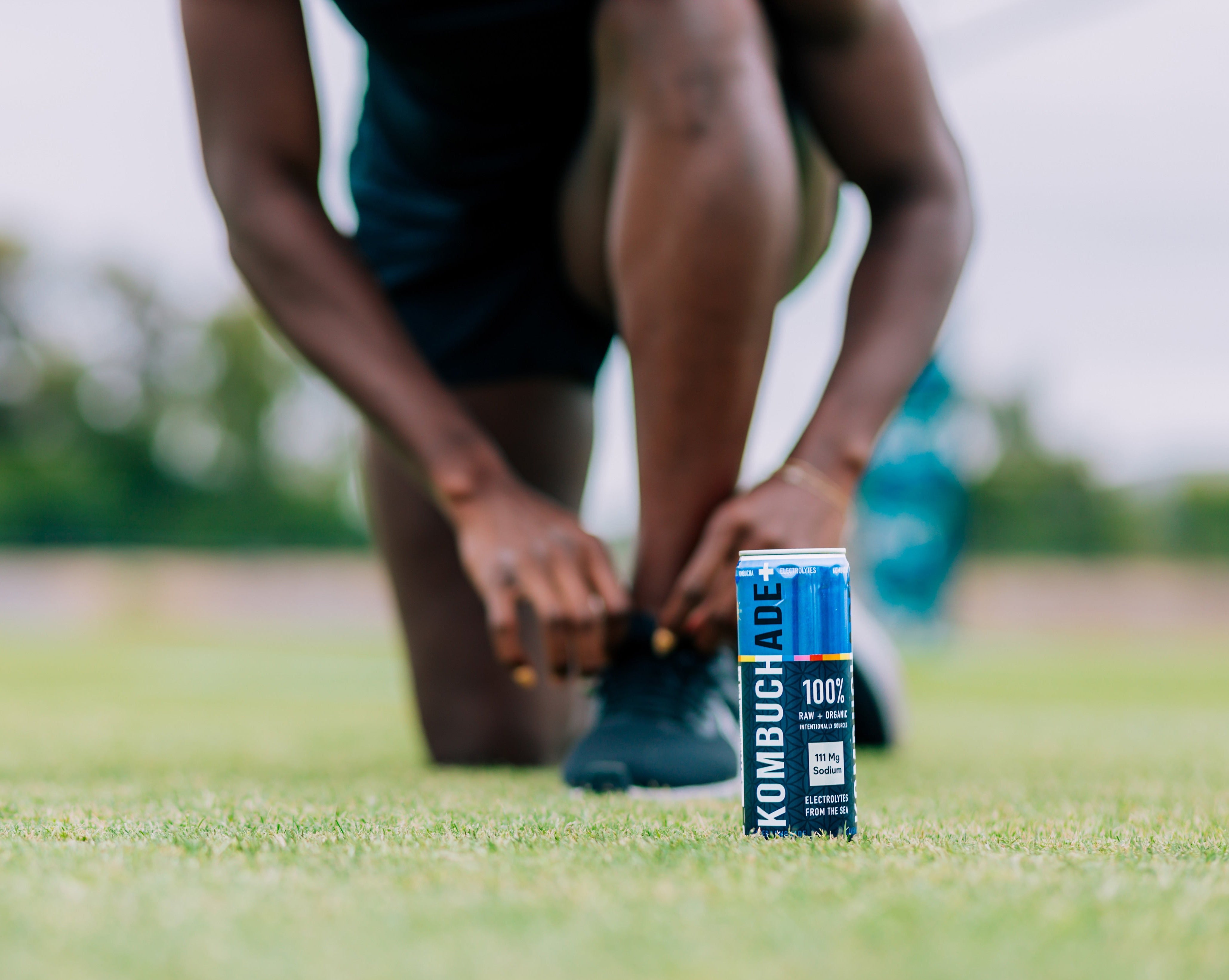rugby athlete tying shoe on ruby field with a can of lavender lemonade Kombuchade