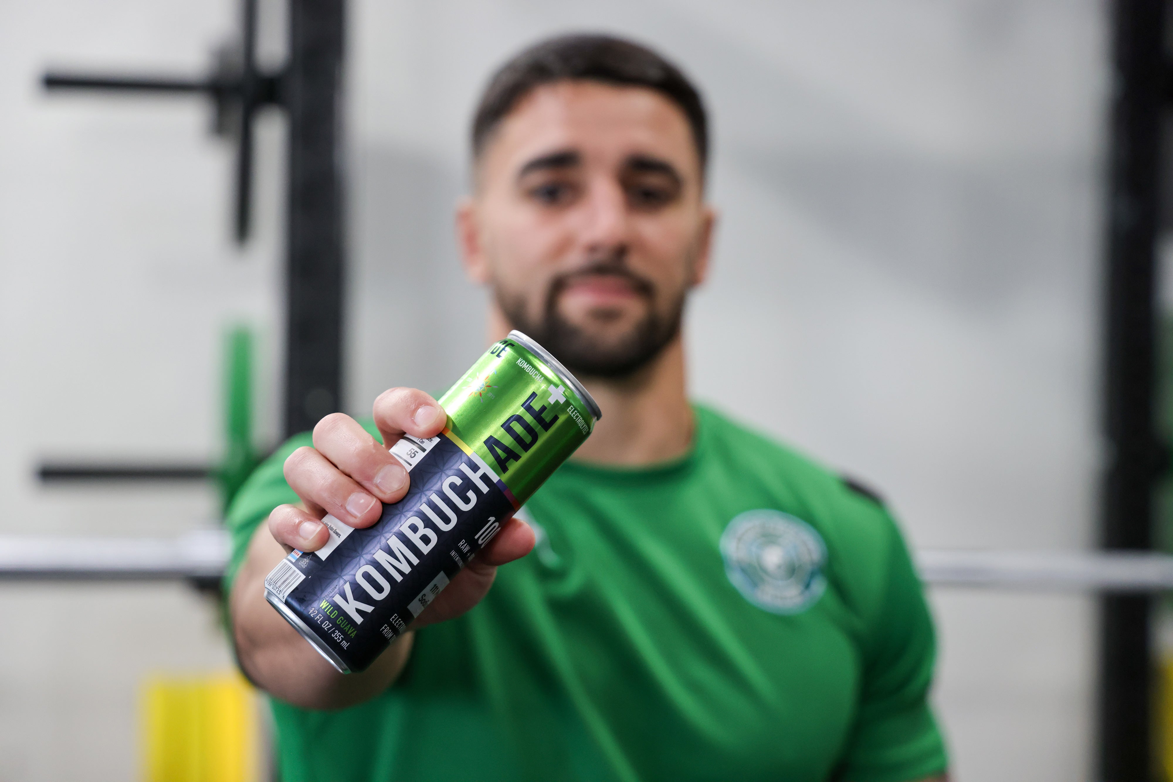 athlete holding a can of wild guava Kombuchade to the camera wearing a Chicago Hounds rugby jersey
