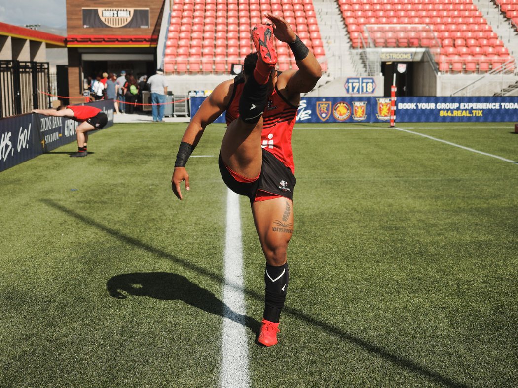 athlete on rugby field warming up in a red jersey
